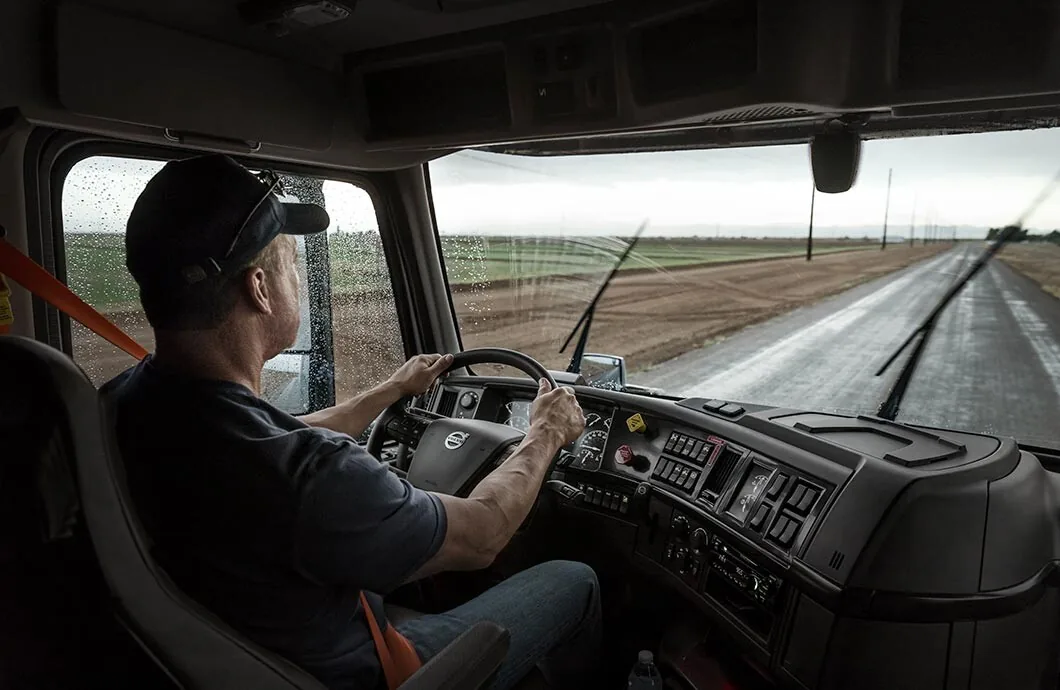 Professional truck driver navigating a wet rural road
